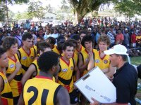 The Boomerangs listen to the coach in Lae, with a big crowd looking on